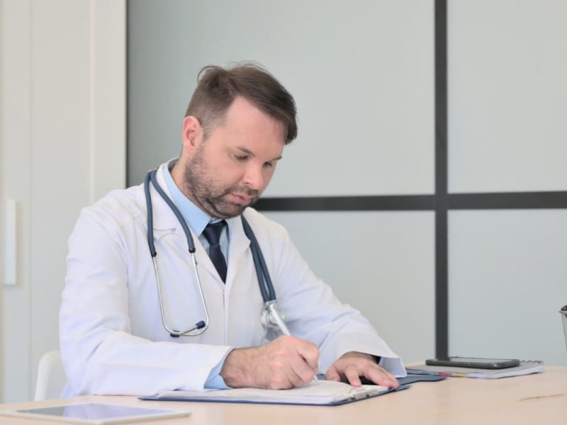 Médico preenchendo a tabela TUSS em documentos.