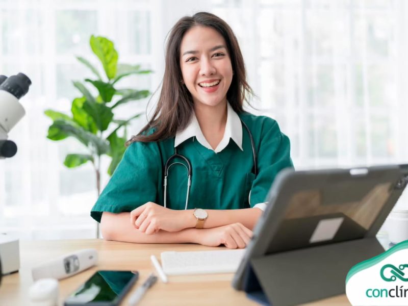 Médica sorrindo em sua mesa de atendimento para telemedicina integrada.