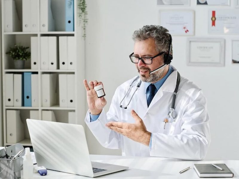 Médico fazendo telemedicina em sua mesa com laptop.